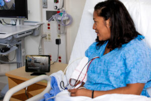 A patient in a hospital bed looks at Amazon's Alexa device.